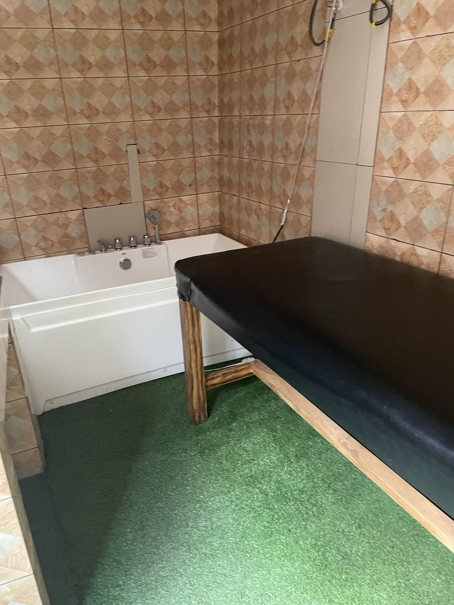 Treatment room with a massage table alongside a bathtub