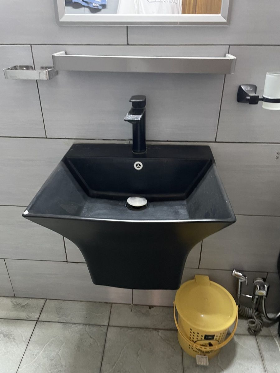 Black vessel basin mounted on a tiled bathroom wall
