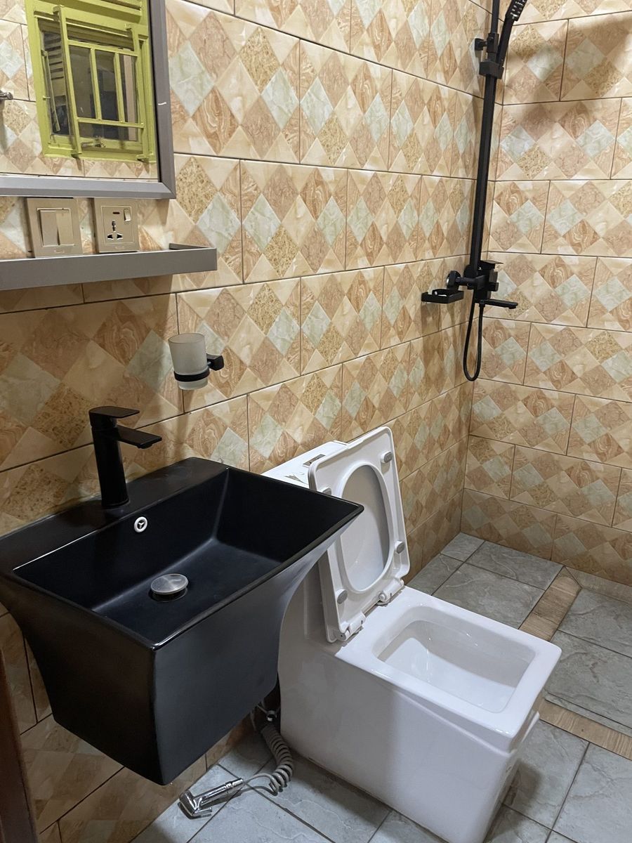 Bathroom with a black basin and bidet against patterned tiles