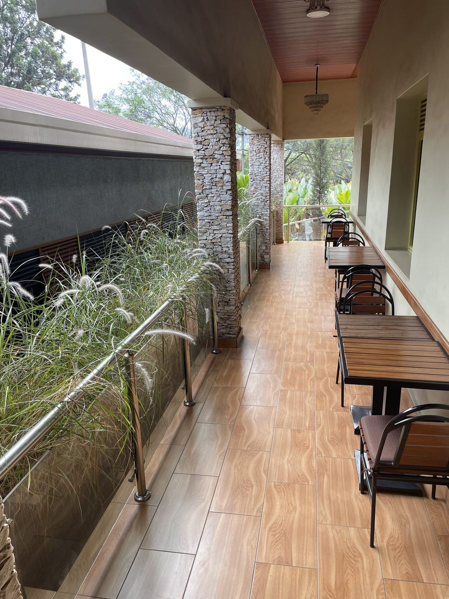 Wooden garden terrace with tables and chairs beside planted beds