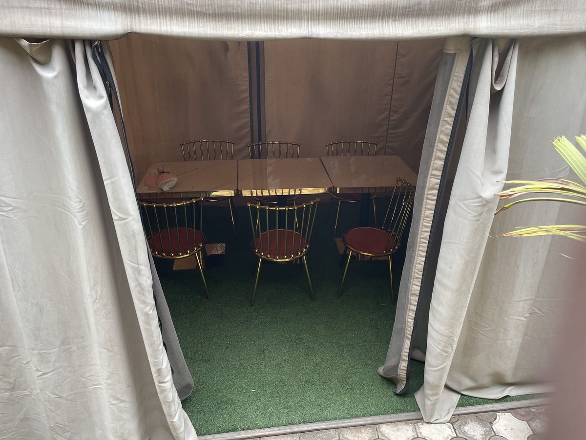Covered event tent laid out with a long table and chairs